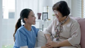 A senior resident using a tablet for video calling while sitting in a comfortable living room chair.