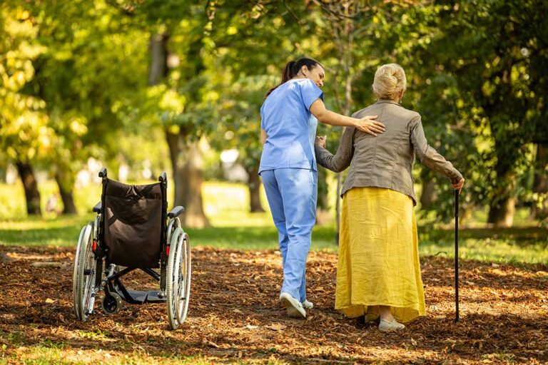 Nurse reviewing a medication list with an older resident and family member at a dining table.