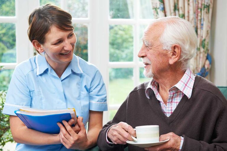 A senior resident greeting family visitors in a comfortable assisted living lobby.